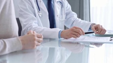 Doktor modern klinikte bir hastaya danışmanlık yapıyor. Sağlık bakımı uzmanı, cam masanın üstünde el kol hareketi yapan bir kadınla tıbbi bilgileri tartışıyor. İlaç..
