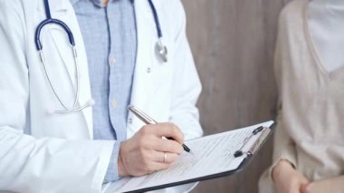 Sağlık bakımı uzmanı doktor, panodaki sağlık raporlarını güncellemeye odaklanmış durumda. İş yerinde tanınmayan bir erkek doktor var. İlaç ve eczane.