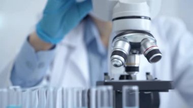 Bir laboratuvar ortamında modern bir mikroskobu ayarlayan bir araştırmacının elleri.