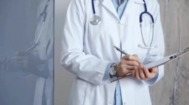 Sağlık sigortası uzmanı doktor bir panoya tıbbi kayıtlar yazıyor. İş yerinde tanınmayan bir kadın doktor var. İlaç ve eczane.