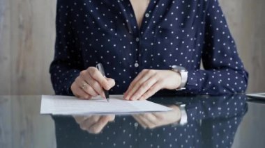 İş kadını ofis masasında üzerinde puantiyeli mavi bluzla şirket sözleşmesi imzalıyor. İş adamları konsepti.