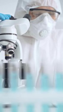 Bir laboratuvar ortamında mikroskop kullanarak örnekleri analiz eden bilim adamı..