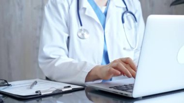 Doktor cam masada otururken klinikte dizüstü bilgisayar kullanıyor. Tıp konsepti.