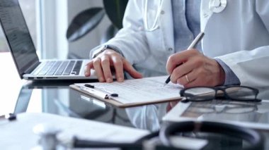 Doktor cam masaya dizüstü bilgisayarla tıbbi kayıtlar yazıyor. İlaç ve Sağlık Hizmetleri.