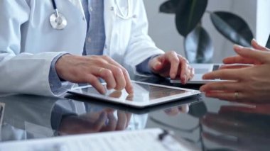 Klinikteki tablet bilgisayarla doktor ve hasta sohbeti. İlaç ve Sağlık Hizmetleri.