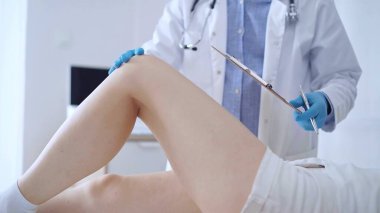 Mavi tıbbi eldiven giyen doktor, bir klinikte tıbbi muayene sırasında hastaların dizlerini muayene eder. Tıp ve ortopedi kavramı..