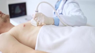 Erkek hastaya göğüs ve kalp ultrasonu uygulayan beyaz tıbbi eldiven giyen doktor kadın. Tıp hizmeti, kardiyoloji.