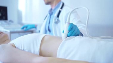 Kadın bir hastanın iç organlarını inceleyen ultrason makinesi kullanan beyaz önlük giyen bir doktor. Tıpta önleyici terapi.