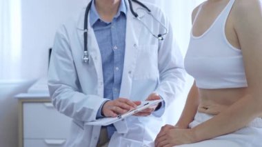 Doktor ve hasta. Doktor, hasta kadın bir şeyler anlatırken bir panoya not alıyor. Tıp konsepti.