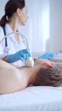 Doktor kadın mavi eldiven giyip erkek hastaya boyun ultrasonu yapıyor. Tıp hizmeti kavramı.
