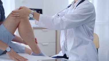 Doktor hastaların dizlerini dikkatlice muayene ediyor. Kişisel bakım ve destek sağlıyor. Tıp ve ortopedik konsept.