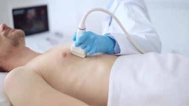 Doktor kadın mavi eldiven giyip erkek hastaya göğüs ultrasonu yapıyor. Tıp hizmeti, kardiyoloji.
