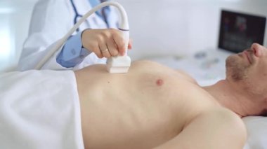 Doktor kadın, erkek hastaya göğüs ve kalp ultrasonu yapıyor. Tıp hizmeti, kardiyoloji.