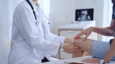 Doktor hastaların dizlerini dikkatlice muayene ediyor. Kişisel bakım ve destek sağlıyor. Tıp ve ortopedik konsept.