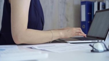 Koyu mavi üniformalı bir kadın ev ofisinden dizüstü bilgisayar klavyesinde daktilo yazıyor. İş konsepti.