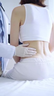 Doktor ve hasta. Klinikte kadın hastayı muayene ederken beyaz eldiven takan bir doktor. Ortopedi ve pediyatri..
