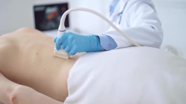 Mavi tıbbi eldiven giyen doktor kadın erkek hastaya ultrason uyguluyor. İlaç ve sağlık hizmetleri.