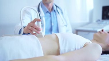 Kadın bir hastanın iç organlarını inceleyen ultrason makinesi kullanan beyaz önlük giyen bir doktor. Tıpta önleyici terapi.