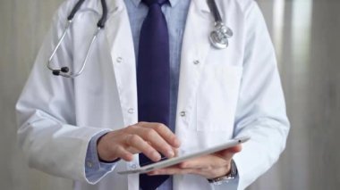 Laboratuvar önlüğü ve steteskop giyen doktor hastanede tablet bilgisayar kullanıyor. Tıp ve Bilim.