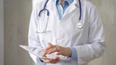 Doktor kadın laboratuvar önlüğü ve steteskop giyiyordu. Hastanede tablet bilgisayar kullanıyordu. Tıp ve bilim konsepti.