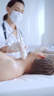 Doktor kadın beyaz önlük giyip erkek hastaya boyun ultrasonu yapıyor. Tıp hizmeti kavramı.