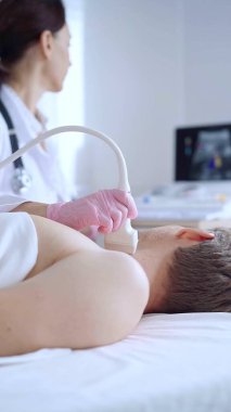 Pembe tıbbi eldivenli doktor kadın erkek hastaya boyun ultrasonu yapıyor. Tiroid bezi muayenesi. Tıp konsepti.