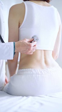 Doktor ve hasta. Doktor steteskop kullanarak kadın ciğerlerini inceliyor. İlaç ve sağlık hizmetleri.