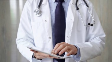 Laboratuvar önlüğü ve steteskop giyen doktor hastanede tablet bilgisayar kullanıyor. Tıp ve Bilim.
