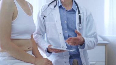 Doktor ve hasta. Doktor, hasta kadın bir şey tarif ederken tablet bilgisayar kullanıyor. İlaç ve sağlık hizmetleri.