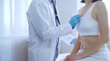 Doktor ve hasta. Mavi tıbbi eldiven giyen hekim klinikte kadın ciğerlerini incelemek için steteskop kullanıyor. Tıp konsepti.