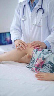 Doktor ve çocuk hasta. Ortopedist, kızların dizlerini klinikte muayene ediyor. İlaç ve sağlık hizmetleri.