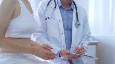 Doktor ve hasta. Doktor, hasta kadın bir şeyler anlatırken bir panoya not alıyor. Tıp konsepti.