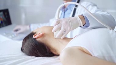 Doktor adam, muayene için kadın hastanın boynuna ultrason cihazı takıyor. Tıp ve Bilim.