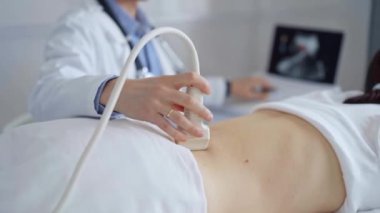 Doktor adam bir hastanın sırtında ultrason cihazı kullanıyor kadın da arka plandaki monitörde sonuçları analiz ediyor. Tıp ve Bilim.