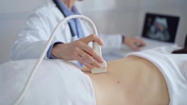 Doktor adam bir hastanın sırtında ultrason cihazı kullanıyor kadın da arka plandaki monitörde sonuçları analiz ediyor. Tıp ve Bilim.