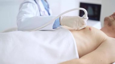 Erkek hastaya göğüs ve kalp ultrasonu uygulayan beyaz tıbbi eldiven giyen doktor kadın. Tıp hizmeti, kardiyoloji.