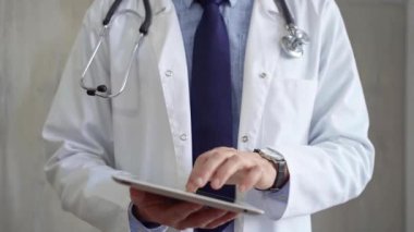 Laboratuvar önlüğü ve steteskop giyen doktor hastanede tablet bilgisayar kullanıyor. Tıp ve Bilim.