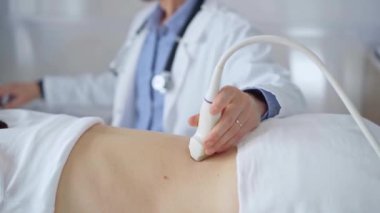 Doktor adam bir hastanın sırtında ultrason cihazı kullanıyor kadın da arka plandaki monitörde sonuçları analiz ediyor. Tıp ve Bilim.
