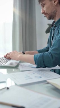 Yeşil tişört giyen girişimci veri analiz çizelgeleriyle dizüstü bilgisayarda çalışıyor. Dikey iş portresi. İş adamları konsepti.