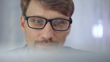 Gözlüklü bir işadamı, yarı saydam bir dizüstü bilgisayar yüzeyi tarafından dikkatle gizleniyor. İş adamları konsepti.