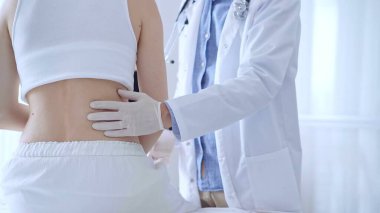 Doktor adam beyaz eldivenler giyip klinikteki kadın hastayı muayene ediyor. Tıp ve ortopedi..