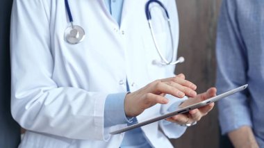 Klinikte dijital tablet kullanan tanınmayan bir kadın doktora danışıyorum. İlaç ve sağlık hizmetleri.