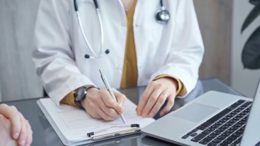 Doktor hastayla evrak işlerini hallediyor. Formları olan doktorların elleri bilgisayara bilgi aktarıyor. İlaç ve sağlık hizmetleri kavramı.