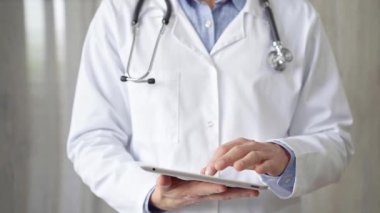 Doktor kadın laboratuvar önlüğü ve steteskop giyiyordu. Hastanede tablet bilgisayar kullanıyordu. Tıp ve bilim konsepti.