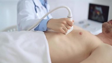 Doktor kadın, erkek hastaya göğüs ve kalp ultrasonu yapıyor. Tıp hizmeti, kardiyoloji.