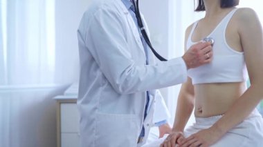 Doktor ve hasta. Doktor, klinikteki kadın ciğerlerini incelemek için steteskop kullanıyor. İlaç ve sağlık hizmetleri.