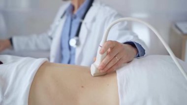 Doktor adam bir hastanın sırtında ultrason cihazı kullanıyor kadın da arka plandaki monitörde sonuçları analiz ediyor. Tıp ve Bilim.