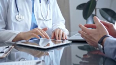 Klinikteki tablet bilgisayarla doktor ve hasta sohbeti. İlaç ve Sağlık Hizmetleri.