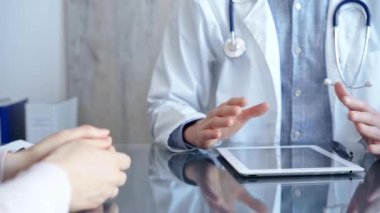 Klinikteki tablet bilgisayarla doktor ve hasta sohbeti. İlaç ve Sağlık Hizmetleri.