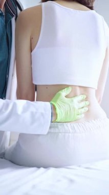 Doktor ve hasta. Klinikteki kadın hastayı muayene eden yeşil eldivenli bir doktor. Ortopedi ve tıp.